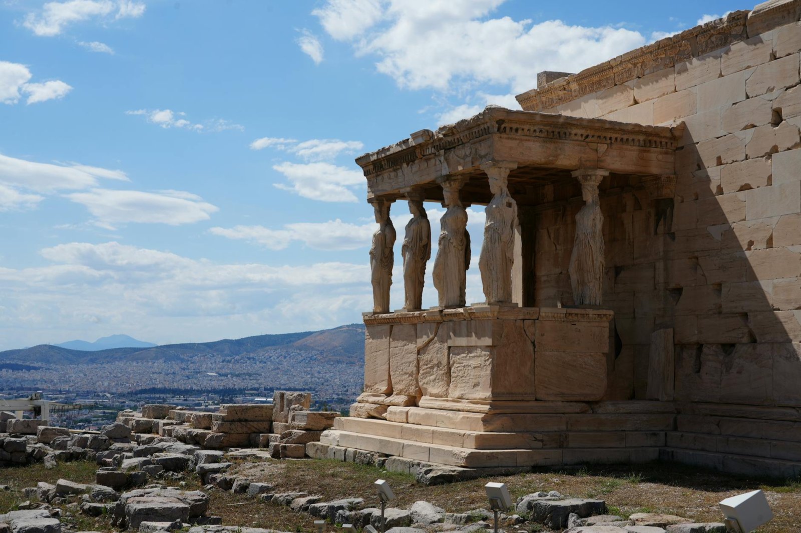 Erechtheion Temple in Athens features iconic Caryatids sculptures under a bright blue sky.