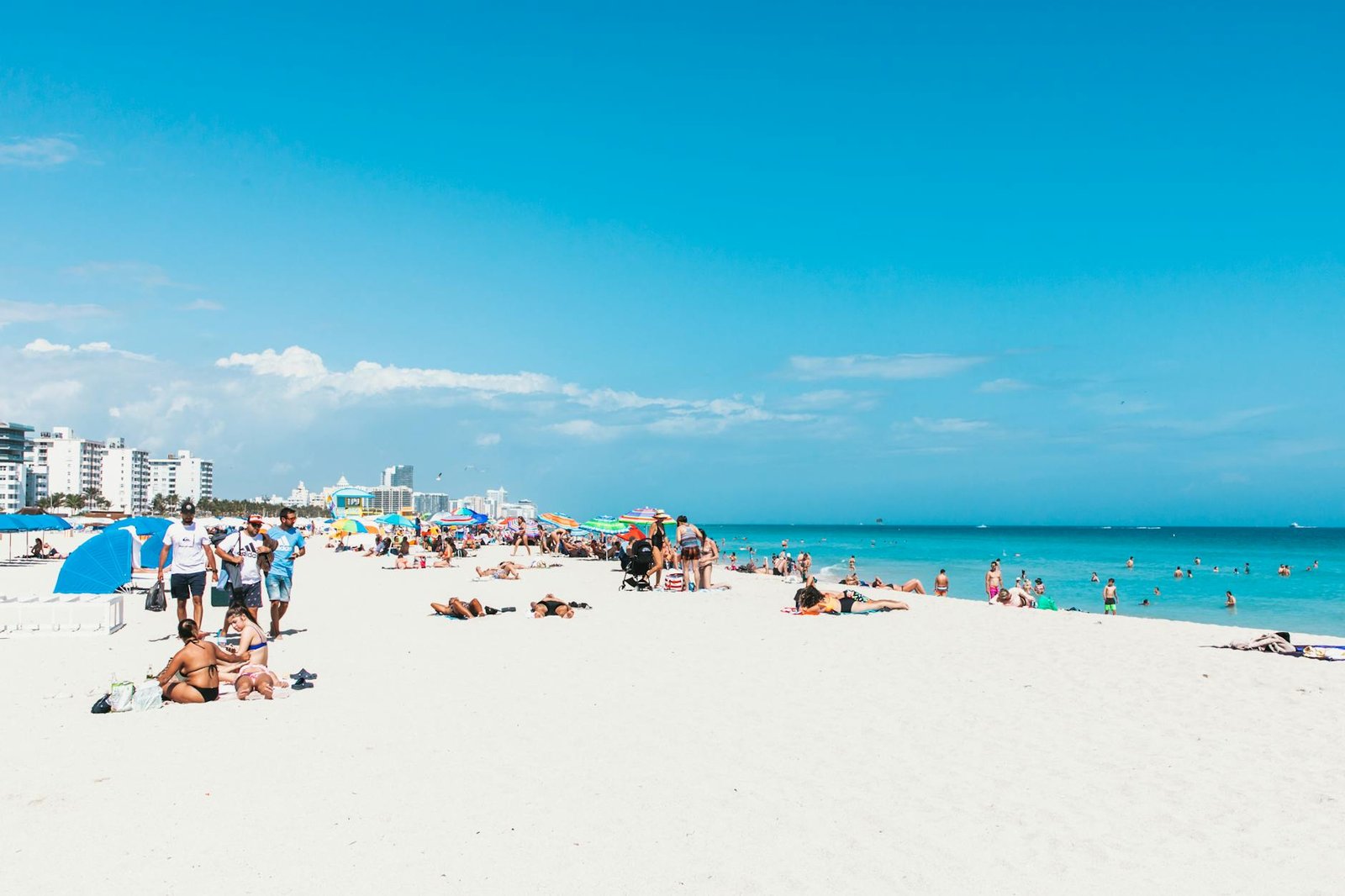 A lively summer day at Miami Beach with sunbathers and colorful umbrellas.